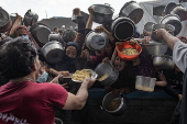 Displaced Palestinians collect donated food in Khan Yunis, southern Gaza
