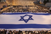 People hold a giant Israeli flag by the Western Wall, in Jerusalem's Old City