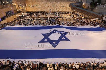 People hold a giant Israeli flag by the Western Wall, in Jerusalem's Old City