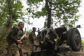 Ukrainian servicemen load a shell into a howitzer as they fire towards Russian troops at a front line in Zaporizhzhia region