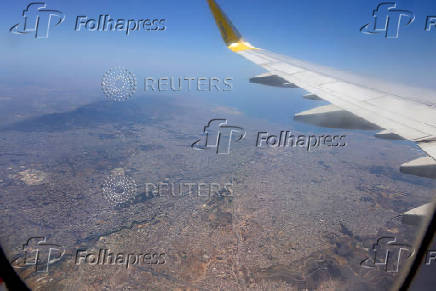 An aerial view through the window of a passenger aircraft of Vueling airlines shows the city of Athens and the peripheral cities, Greece