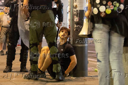 Serbian police stand next to a detained protester during standoff  between ruling party supporters and anti-government protesters in Belgrade