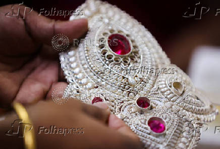 A goldsmith inserts a stone inside a silver crown at a jewellery making workshop in Mumbai