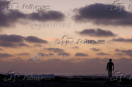 Surfer leaves the oceen after sunet in California