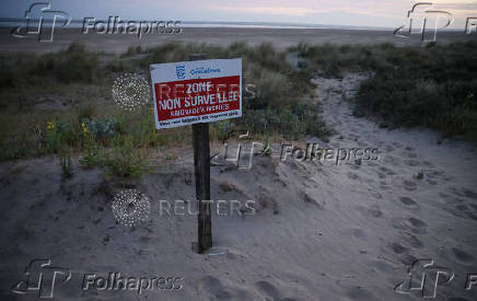 A sign warning people about the dangers of swimming stands on the beach at Gravelines