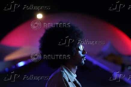 A man with a afro hairstyle poses for a portrait poses in front of the 