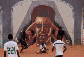 Men play soccer near a graffiti mural in Yoff, neighborhood of Dakar