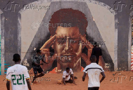 Men play soccer near a graffiti mural in Yoff, neighborhood of Dakar