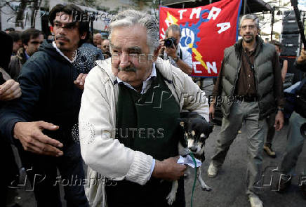 FILE PHOTO: Uruguayan President Jose Mujica arrives for the celebration of the Worker's Day carrying his pet dog Manuela