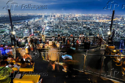 Tourists enjoy a view at the Mahanakhon Skywalk rooftop in Bangkok