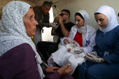 A health worker holds a Palestinian child who was brought to Jordan through King Hussein Bridge crossing to receive medical treatment, in Amman