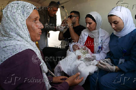 A health worker holds a Palestinian child who was brought to Jordan through King Hussein Bridge crossing to receive medical treatment, in Amman
