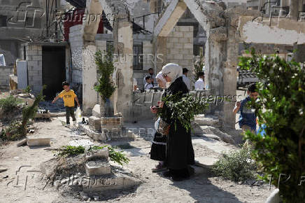 People visit the graves of their relatives at a cemetery, on the first day of the Muslim holiday of Eid al-Adha, in Damascus