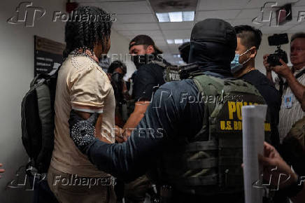 A migrant is detained by federal immigration officers at U.S. immigration court