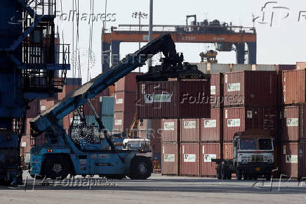 A mobile crane carries a container at Deendayal Port in Kandla
