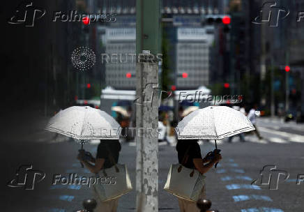 A woman holding a parasol walks on the street in Tokyo