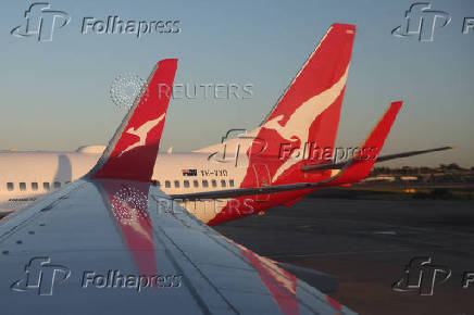 A Qantas logo is visible on the tail of an aeroplane at an airport in Sydney