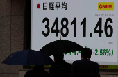 Pedestrians walk past a stock quotation board showing Nikkei share average outside a brokerage in Tokyo