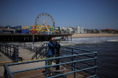 A visitor looks through a telescope along the Santa Monica Pier in Santa Monica
