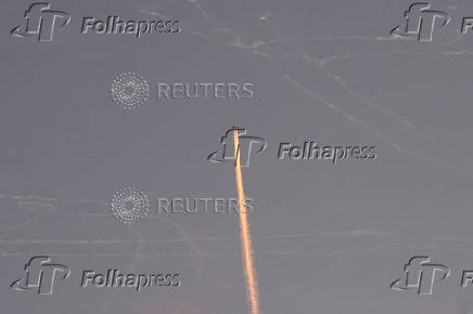 A military aircraft flies in the sky following a barrage of missiles launched from Iran, as seen over Tubas