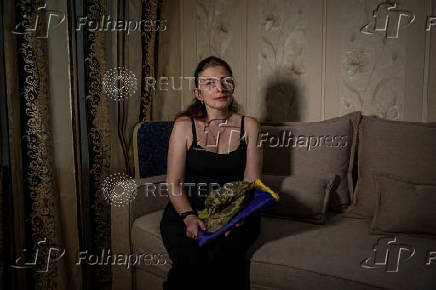 Widow of Ukrainian serviceman, who was born and raised in Enerhodar, and killed at the front line, poses for photo at home, in Zaporizhzhia