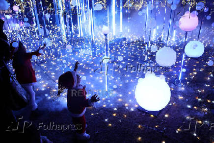 A girl and boy wearing Santa Claus costumes try to catch soap bubbles in the air at an illumination event celebrating the upcoming the Christmas season