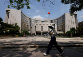 Person walks past the headquarters of the People's Bank of China, in Beijing