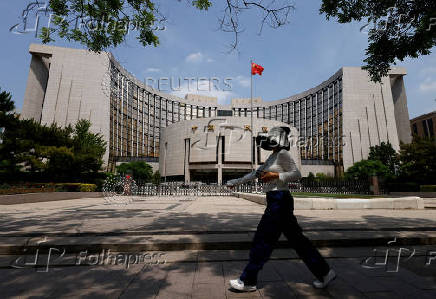 Person walks past the headquarters of the People's Bank of China, in Beijing