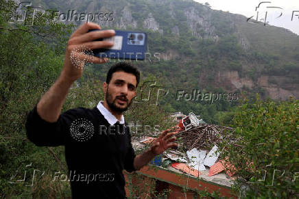 A media person films next to a damaged portion of Bilal Mosque after it was hit by an Indian strike in Muzaffarabad