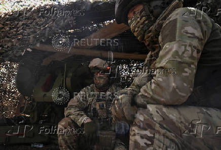 Members of the National Police Special Purpose Battalion wait next to a howitzer at their position on a front line in Zaporizhzhia Region