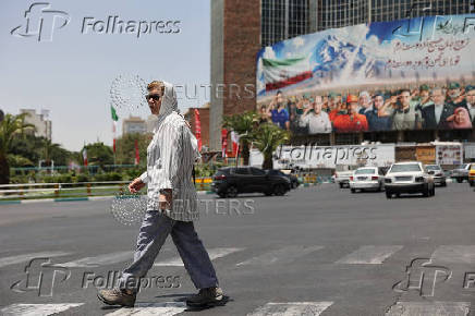A woman walks next to billboard in Tehran