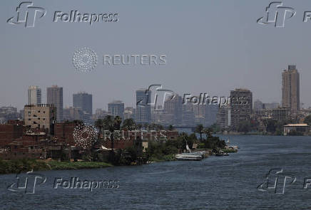 A general view of a farmland with houses on small island next to crowded residential buildings and bridges on the bank of River Nile, in Cairo