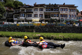 Sports enthusiasts compete while floating on inner tyre tubes during the tyre festival 'Bunar Fest' in Prizren