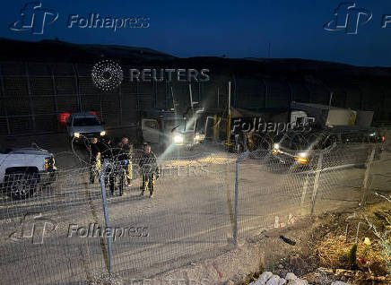 Israeli soldiers stand guard next to a gate on the Golan Heights side
