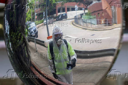 A worker's reflection is seen in a mirror while spraying insecticide at a public housing estate, following reports of imported cases of Chikungunya in Hong Kong