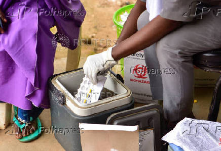A Nigerian health official prepares to administer a mpox vaccination to a woman
