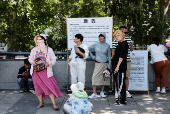 People stany in shade amid a yellow alert for heat, in Shanghai