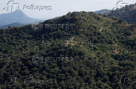 Power lines connecting pylons of high-tension electricity are seen next to a house in a mountain, near Atajate