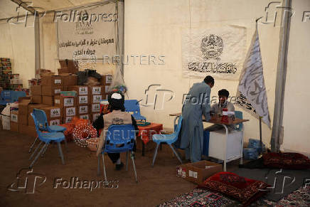 Afghan nationals, who were deported from Iran, sit in a camp for returning migrants near the Islam Qala border crossing