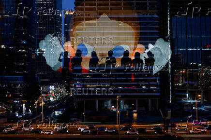 The reflection of silhouettes of people is visible on a glass on a terrace of a shopping mall overlooking Beijing's (CBD)