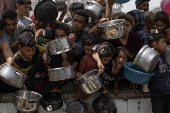 Displaced Palestinians collect donated food in Jabalia, northern Gaza