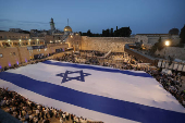 People hold a giant Israeli flag by the Western Wall, in Jerusalem's Old City