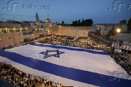 People hold a giant Israeli flag by the Western Wall, in Jerusalem's Old City