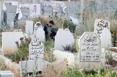 Palestinians visit graves of their relatives at a cemetery in Jenin camp
