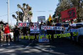 Protestors stand at the entrance to Kibbutz Nir Oz, on the day Israeli PM Netanyahu visits for the first time since the October 7, 2023 attack