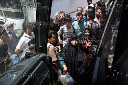 Afghan nationals deported from Iran wait to board a bus upon their arrival at the Islam Qala border crossing