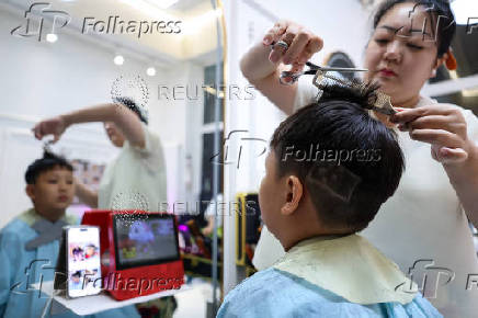 Hair salon owner Xueru gives a child a haircut in a design of a Chinese national flag to commemorate the 80th anniversary of the end of World War Two in Beijing