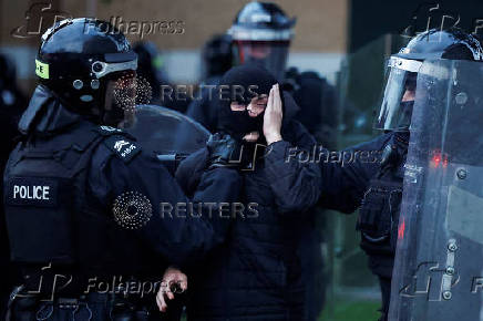 Armed police in riot gear stand guard during a second night of riots, in Ballymena