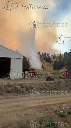 Helicopter dumps water over raging fire in Oregon's Jefferson County