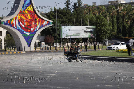 People gather near a damaged site, in Damascus